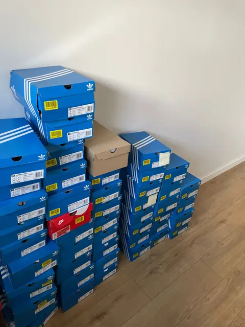 Adidas boxes stacked two deep against a wall